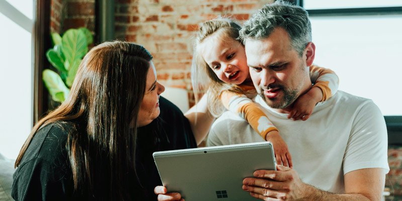 Familia joven de padre, madre e hija mirando contenido de tablet en su casa
